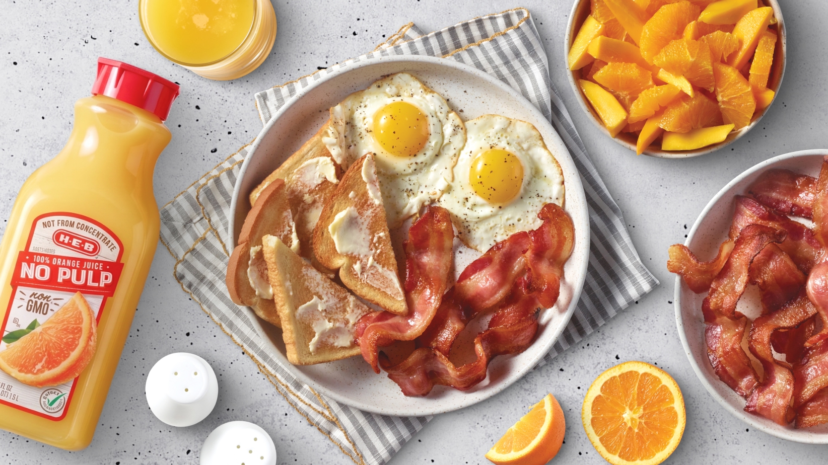Organic orange juice, eggs, toast, bacon on a plate