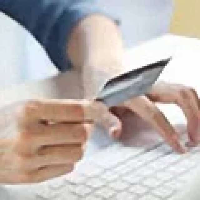 Hands holding a payment card over a keyboard