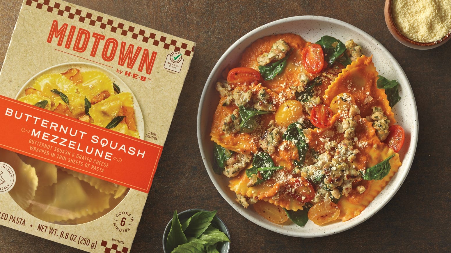 Midtown by H‑E‑B Butternut Squash Mezzelune pasta package and prepared dish with cherry tomatoes, spinach, and crumbled cheese, garnished with fresh basil leaves.