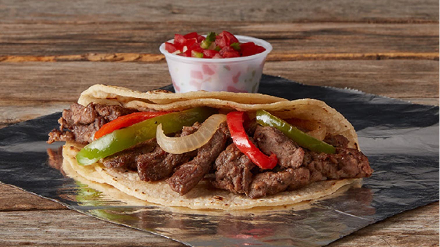 A taco with peppers on a sheet of foil