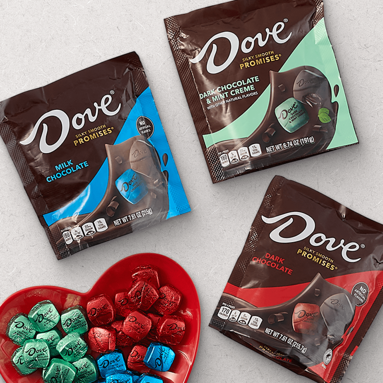 Assorted Dove chocolate bags including Milk Chocolate, Dark Chocolate, and Dark Chocolate & Mint Creme flavors, with individually wrapped chocolates in a heart-shaped dish.