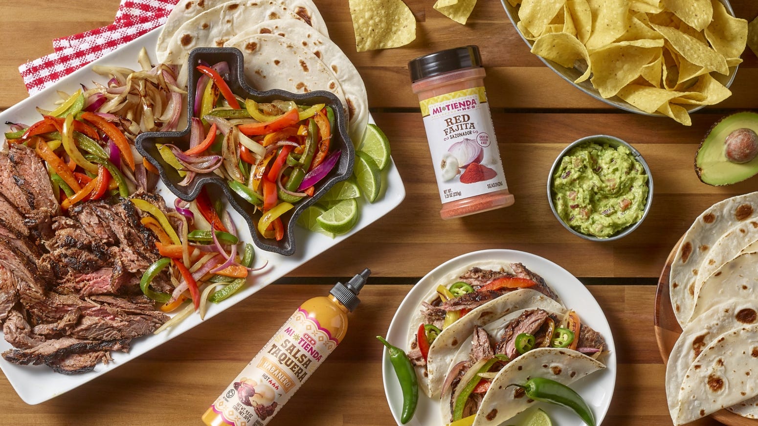 A plate of fajitas with tortilla chips, guac, and salsa