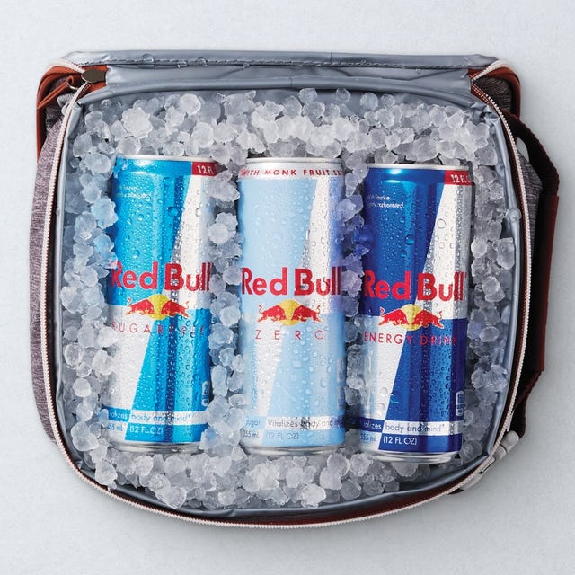 Two cans of Red Bull Winter Edition Fuji Apple & Ginger energy drink, one regular and one sugar-free, placed on a bed of ice.