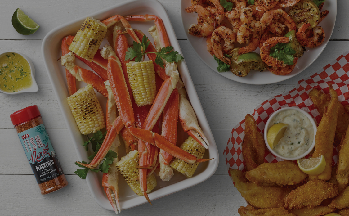Plates of seafood including corn, crab legs, fried fish, shrimp, limes and seasonings