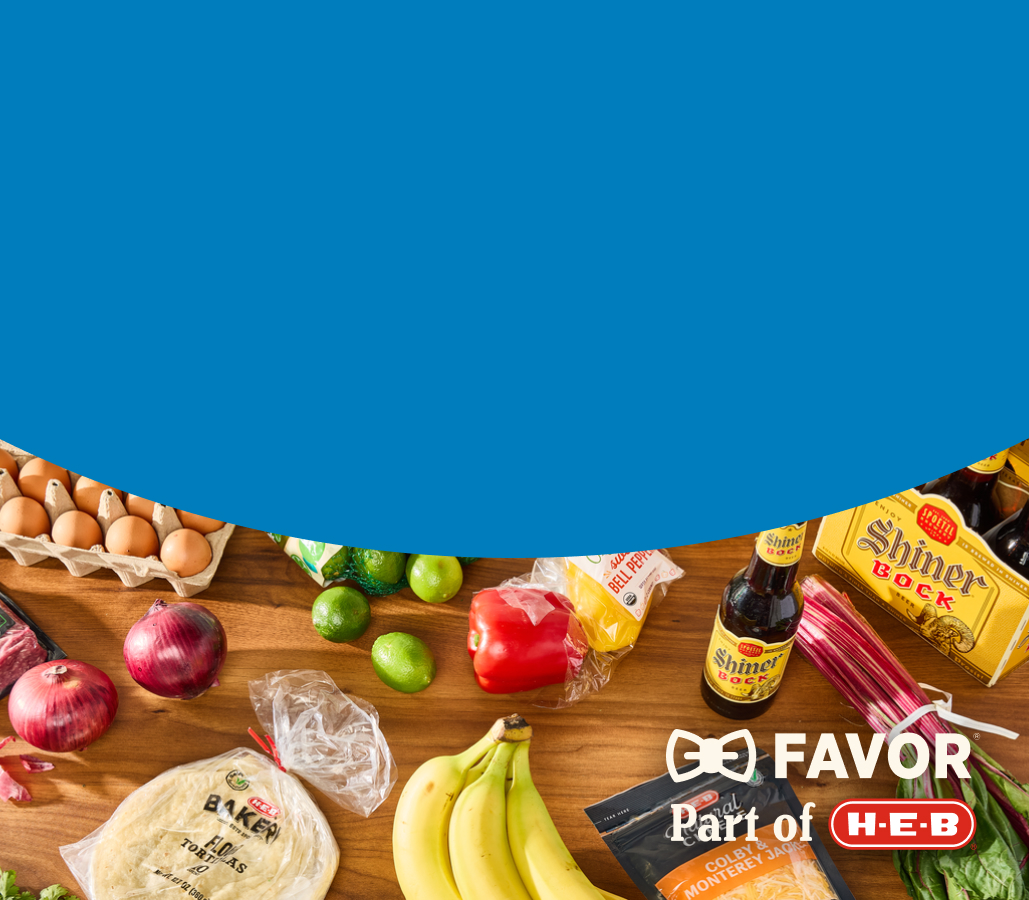 A phone displaying H‑E‑B Favor Now, with a variety of groceries in the background