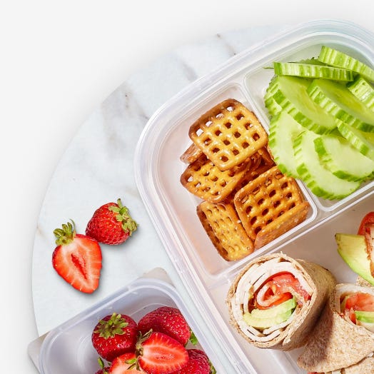 Kid's lunch with a wrap, cucumbers, pretzels, and strawberries